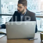 Мъж работи концентрирано върху лаптоп в подредена среда